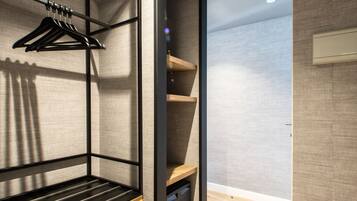 A modern, compact room with a built-in bed, wooden flooring, and a wall-mounted shelf unit.