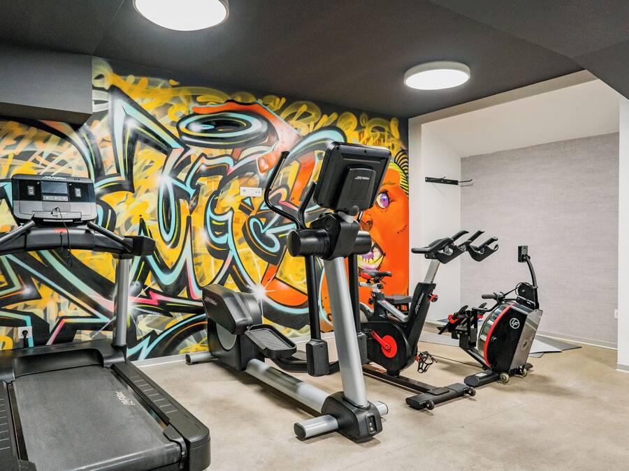 Un gimnasio con bicicleta estática, elíptica y cinta de correr.