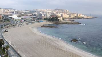 Un paisaje urbano costero con una amplia playa de arena, un estadio y una combinación de edificios residenciales y comerciales.