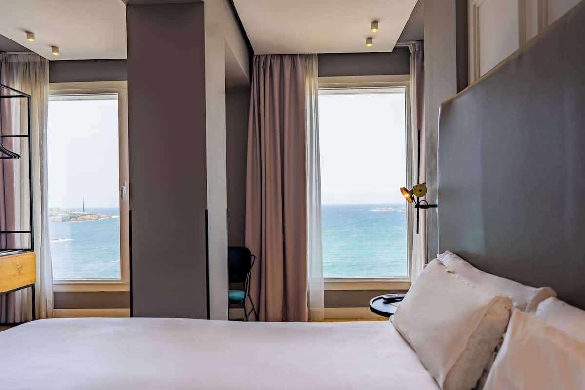Hotellihuone, jossa on suuri sänky, merinäköala ja pieni pöytä.
