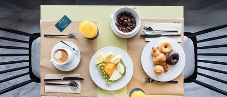 Una mesa de desayuno con platos de comida, una taza de café y un vaso de zumo de naranja.