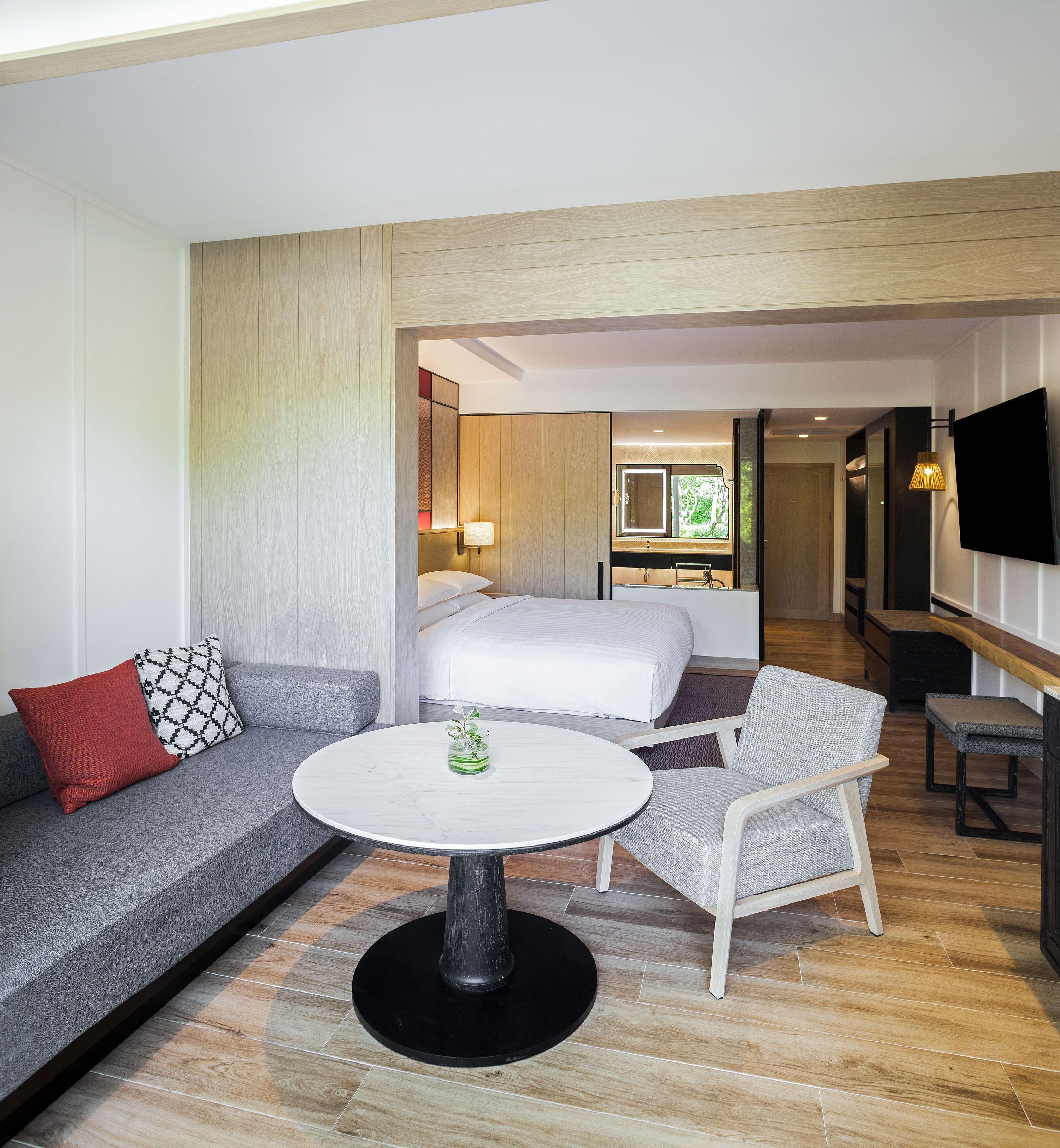 Une chambre d’hôtel avec un lit, un canapé, une chaise, une table ronde et un téléviseur.