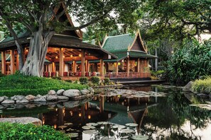 A traditional wooden building with a covered porch and a pond with lily pads. - Hyatt Regency Hua Hin (Hua Hin)