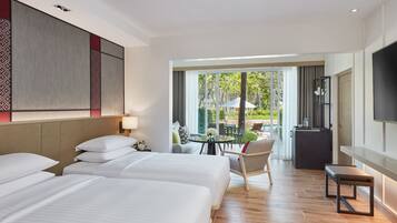 A hotel room with two beds, a dining area with a table and chairs, and a view of the outdoors.