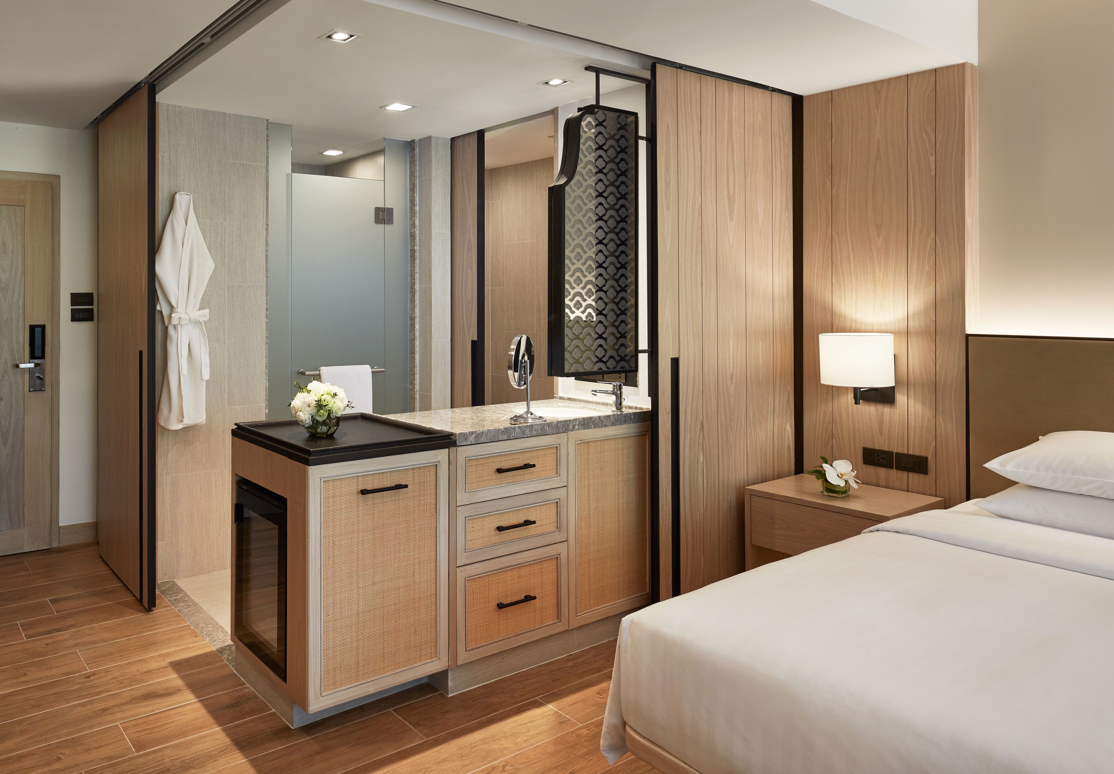 A modern hotel room with a large bed, a bathroom with a vanity, and a mirror.