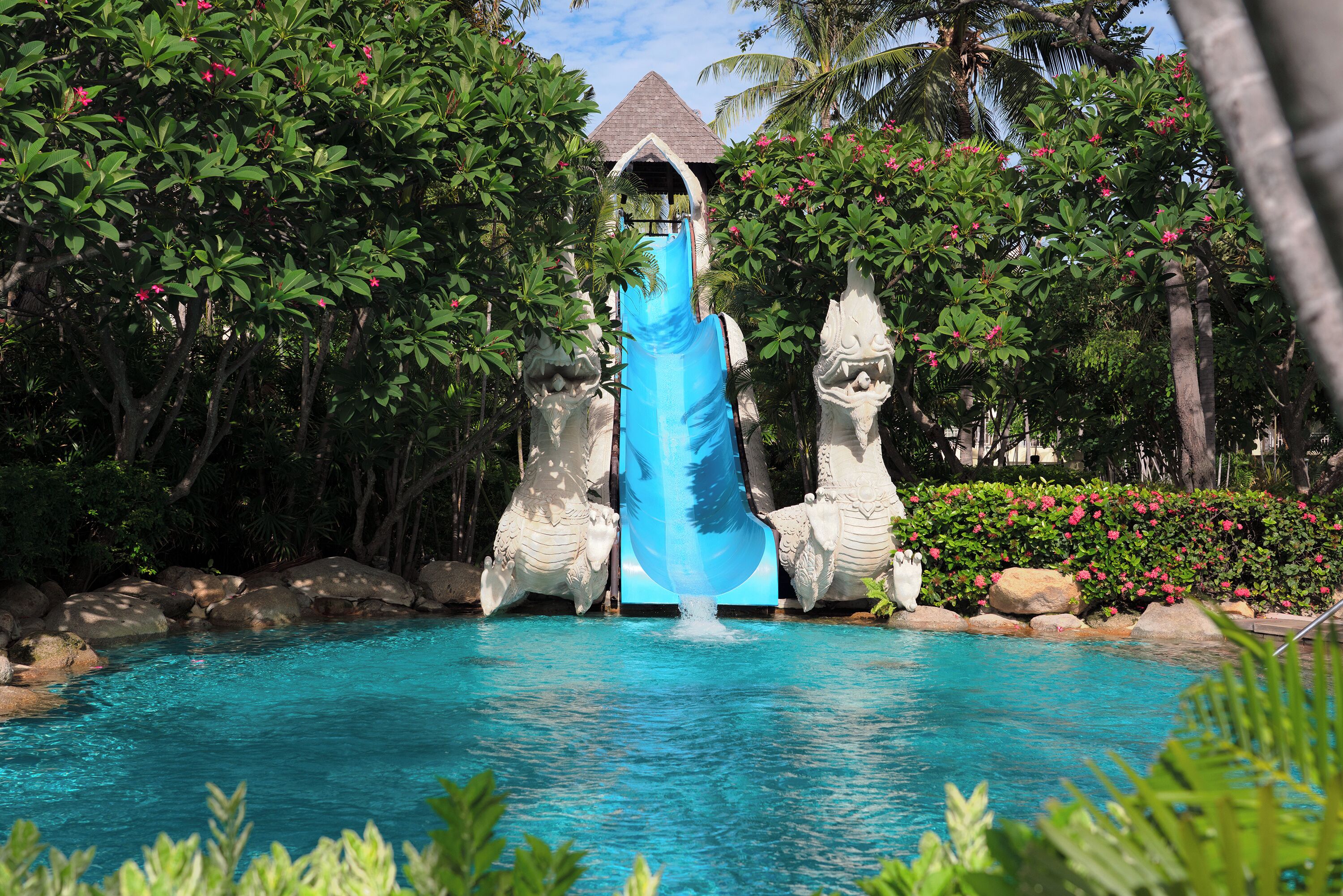 A water slide with a blue slide and a pool at the bottom.