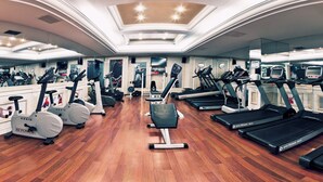 Uma academia com diversos equipamentos de cardio, aparelhos de musculação e espelhos nas paredes.