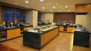 Disposição de buffet com diversas estações de comida, balcão de mármore e design de interiores moderno.