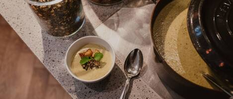A bowl of soup with seeds and a spoon on a speckled countertop.