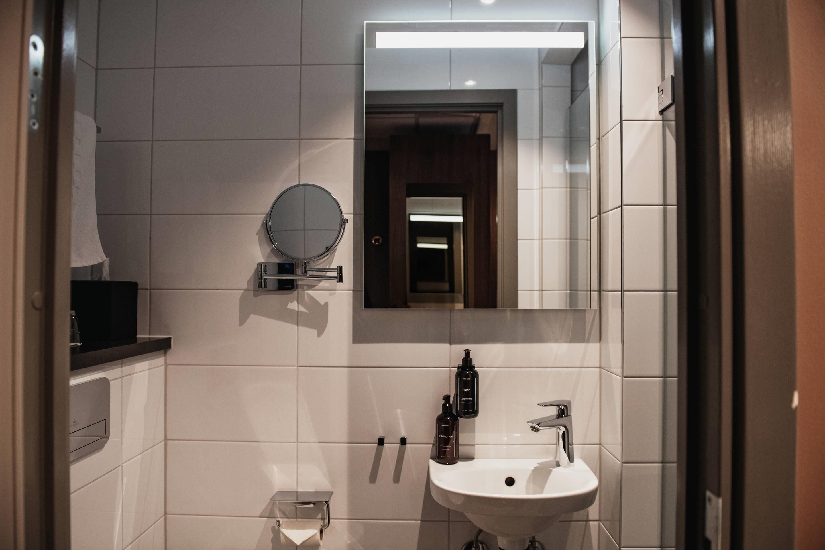 Ein modernes Badezimmer mit einem weißen Waschbecken, einem Spiegel und einem Handtuchhalter.