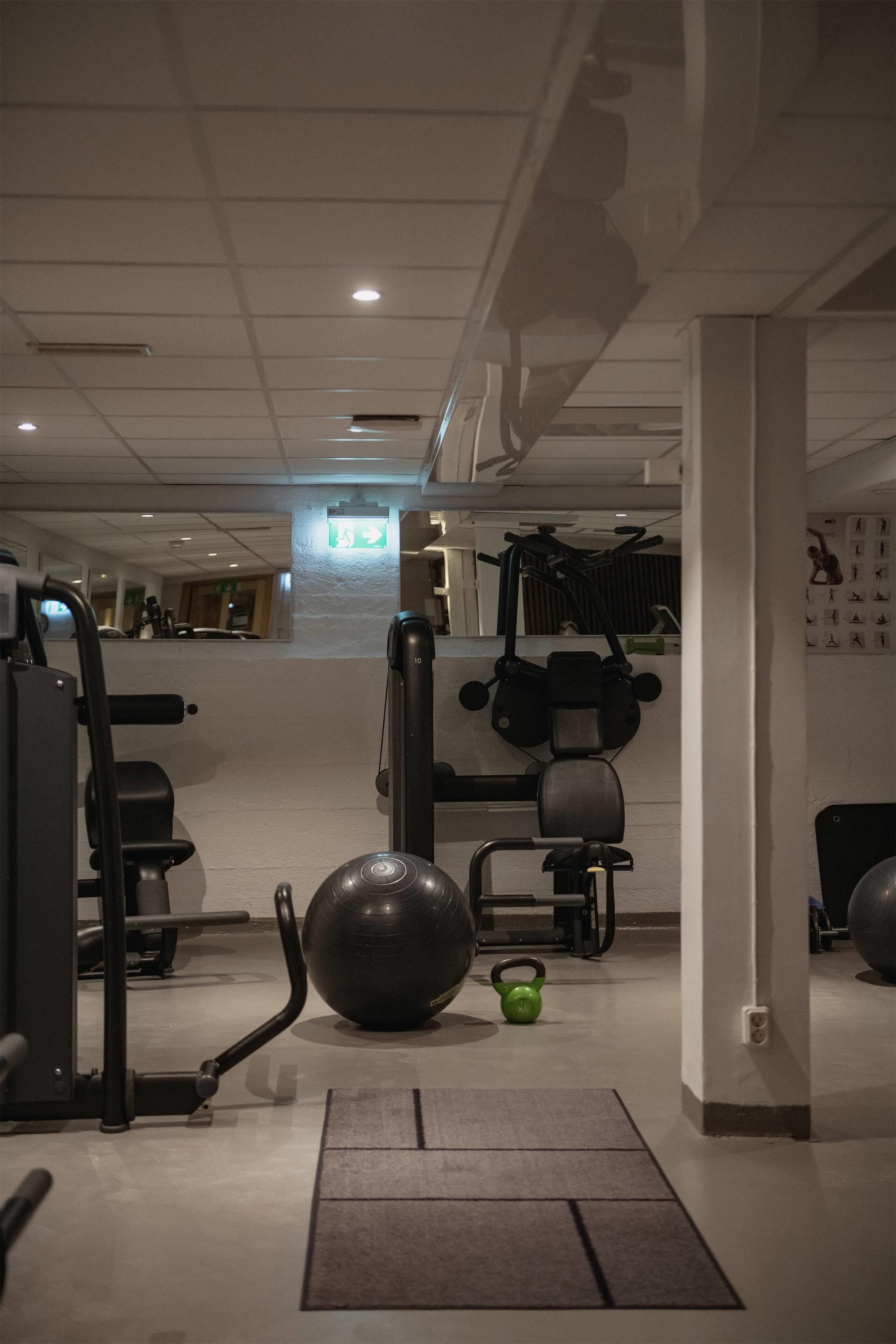 A gym with exercise equipment, a green kettlebell, and a mat.