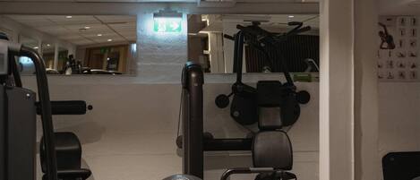 A gym with exercise equipment, a green kettlebell, and a mat.