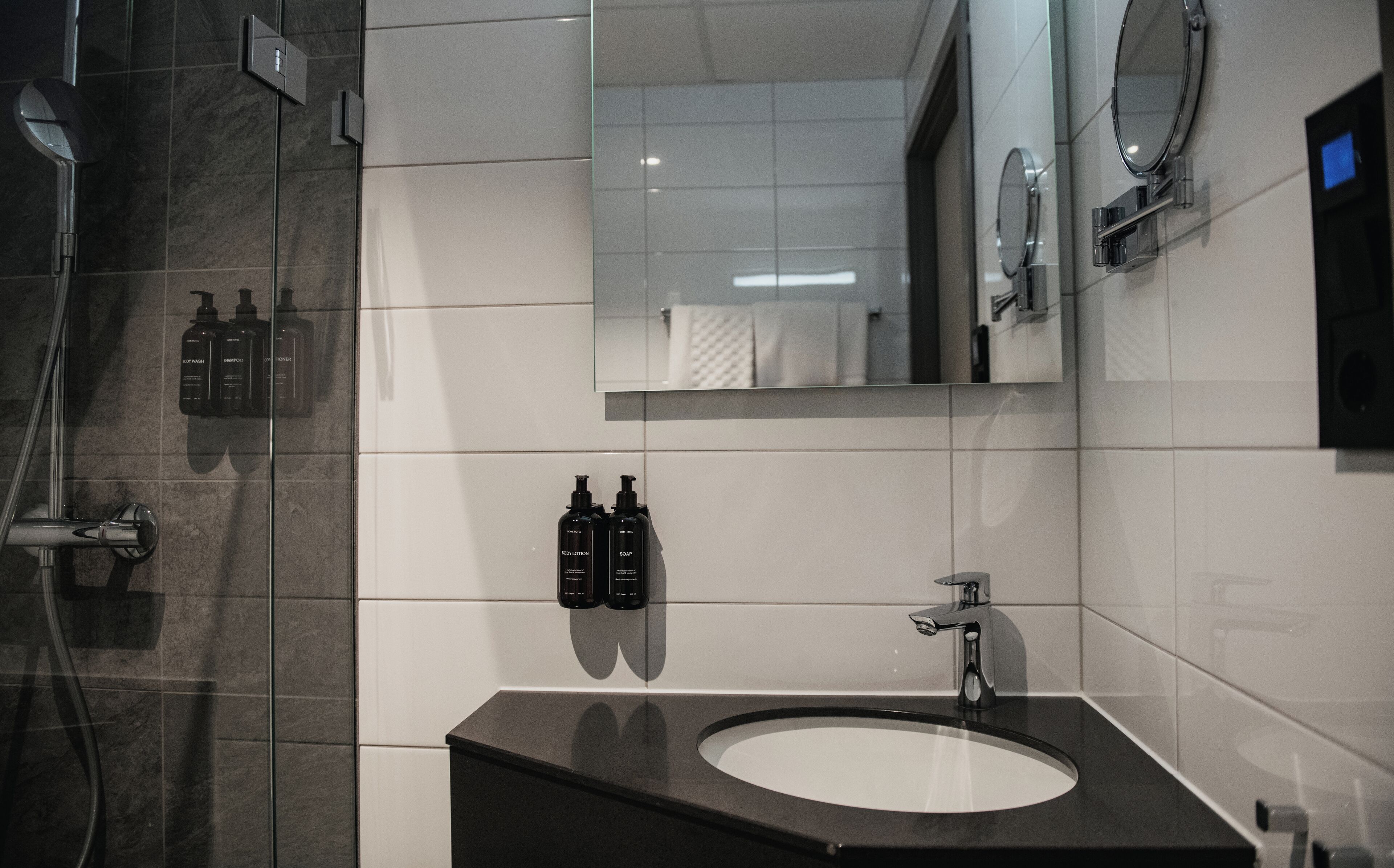 A modern bathroom with a black sink, a mirror, and toiletries on the wall.