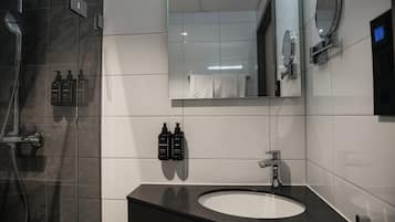 A modern bathroom with a black sink, a mirror, and toiletries on the wall.