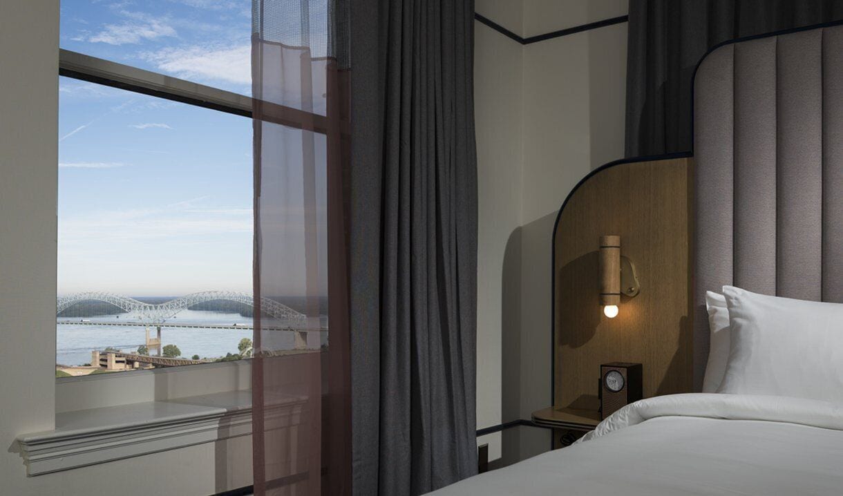 A hotel room with a large window offering a view of a bridge and water.