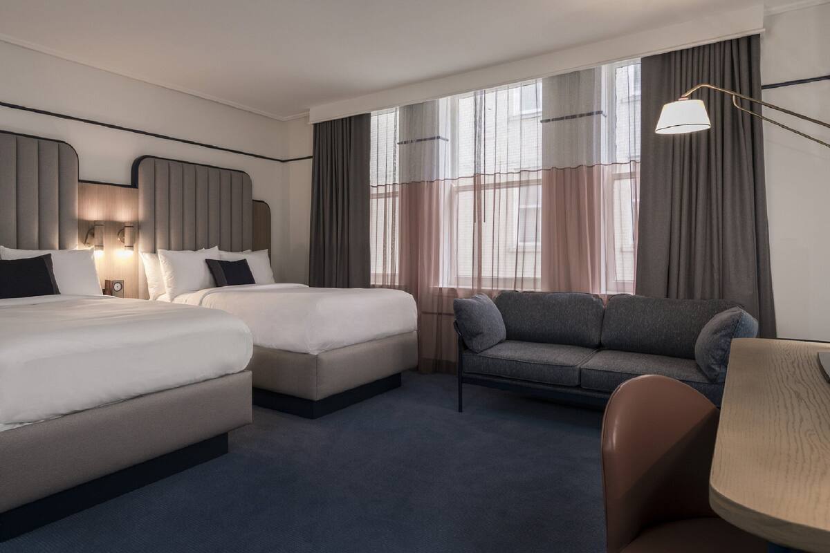 Habitación de hotel con dos camas, un sofá y un escritorio.