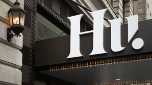 Placa de hotel com um 'H' grande e um acessório de iluminação à esquerda.