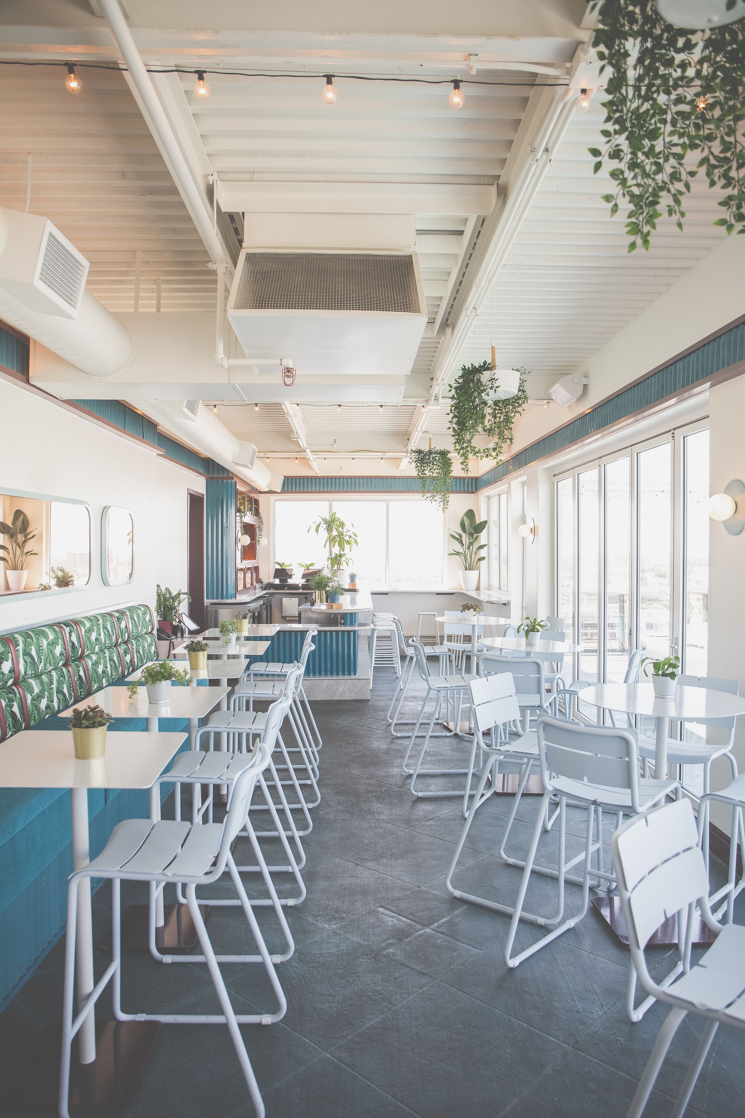 A restaurant interior with high ceilings, exposed ductwork, and a mix of seating arrangements including booths and tables.