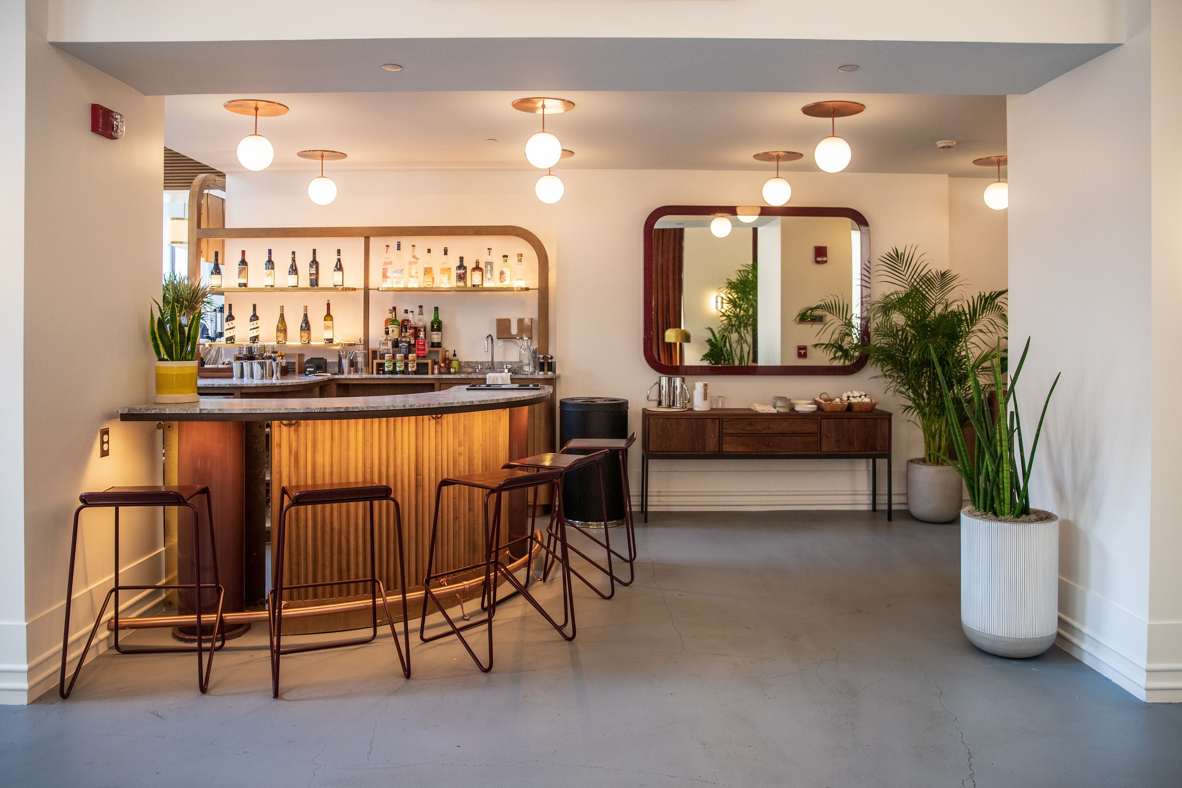 Een moderne bar met krukken, een aanrecht en diverse flessen.