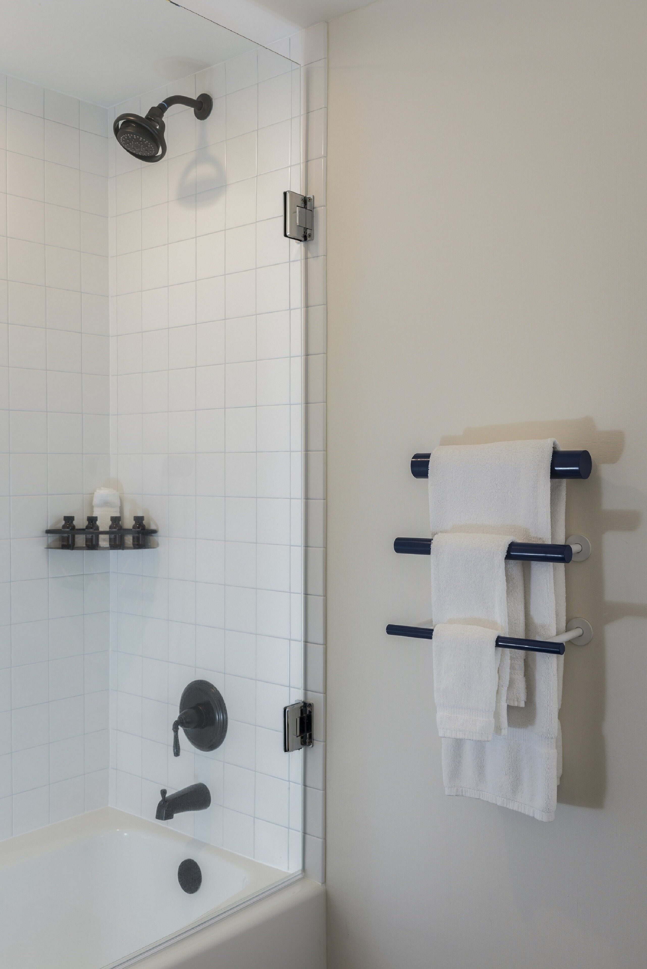 Un baño moderno con bañera, cabezal de ducha y toallero con varias toallas.