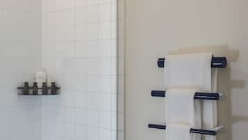 Un baño moderno con bañera, cabezal de ducha y toallero con varias toallas.