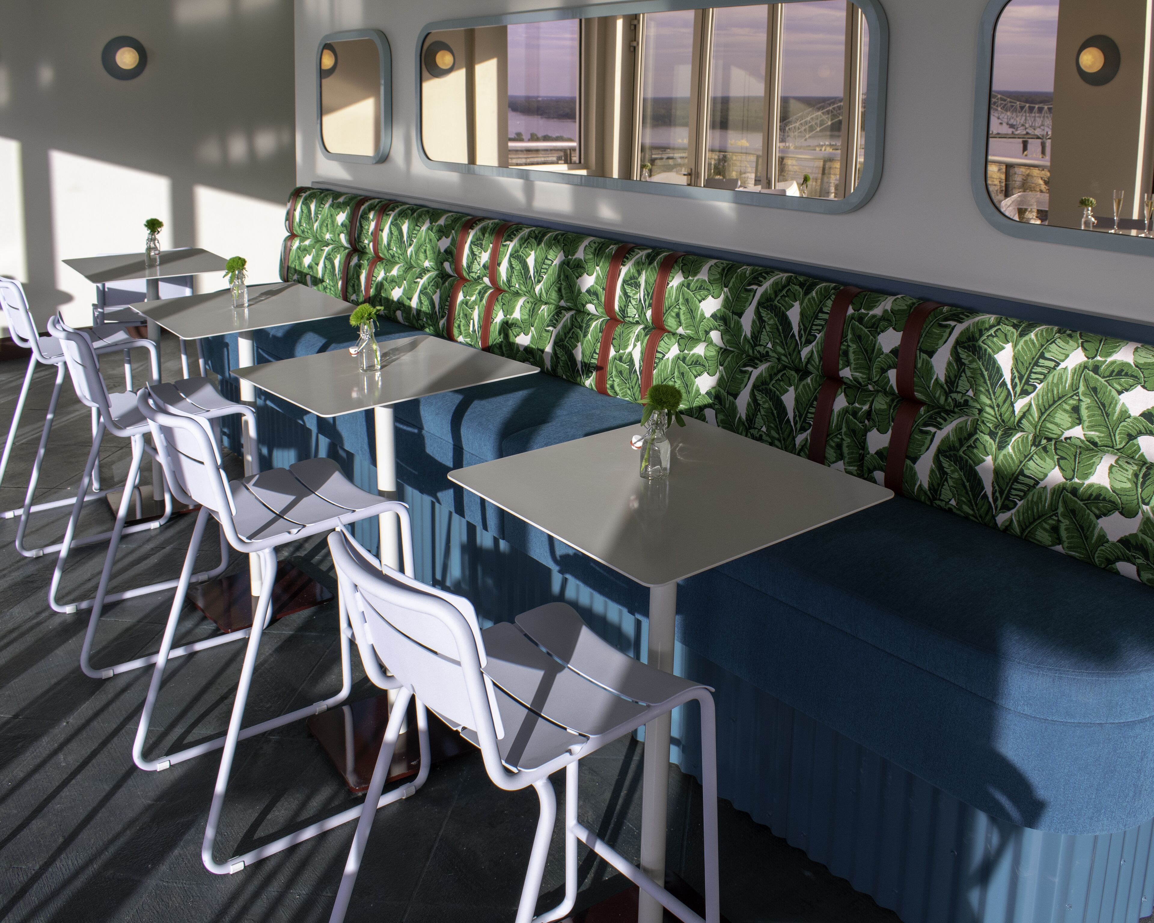 Un espace repas avec des tables et des chaises, un banc et une vue par la fenêtre.