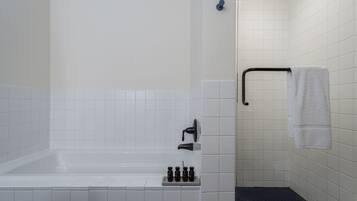 Un baño con bañera, ducha y barra para toallas.
