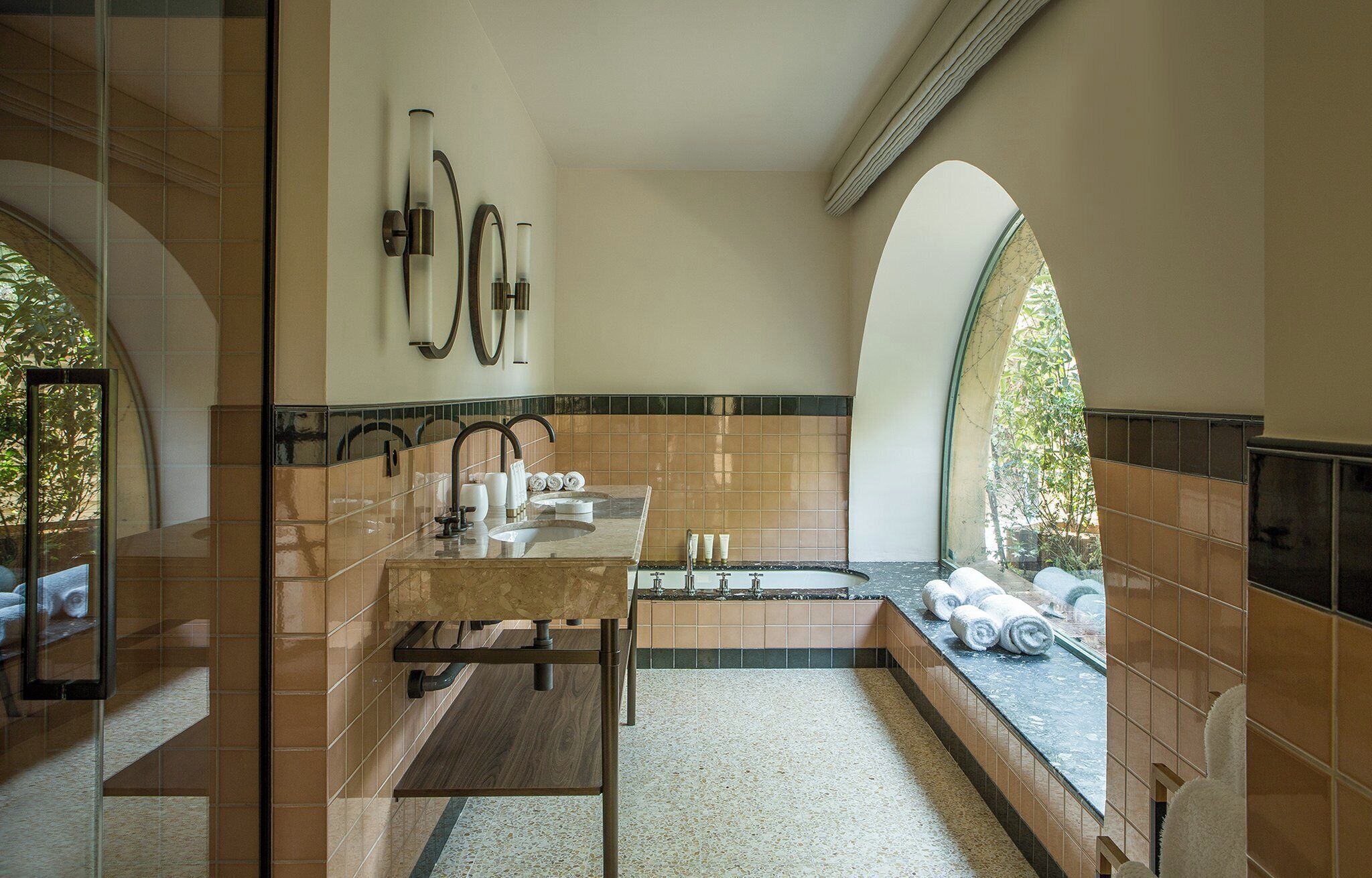 Un bagno moderno con un lavandino freestanding, una vasca e un'ampia finestra che lascia entrare la luce naturale.
