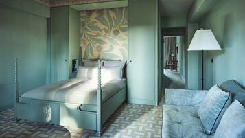 A bedroom with a bed, a nightstand, a dresser, a lamp, and a patterned wall.