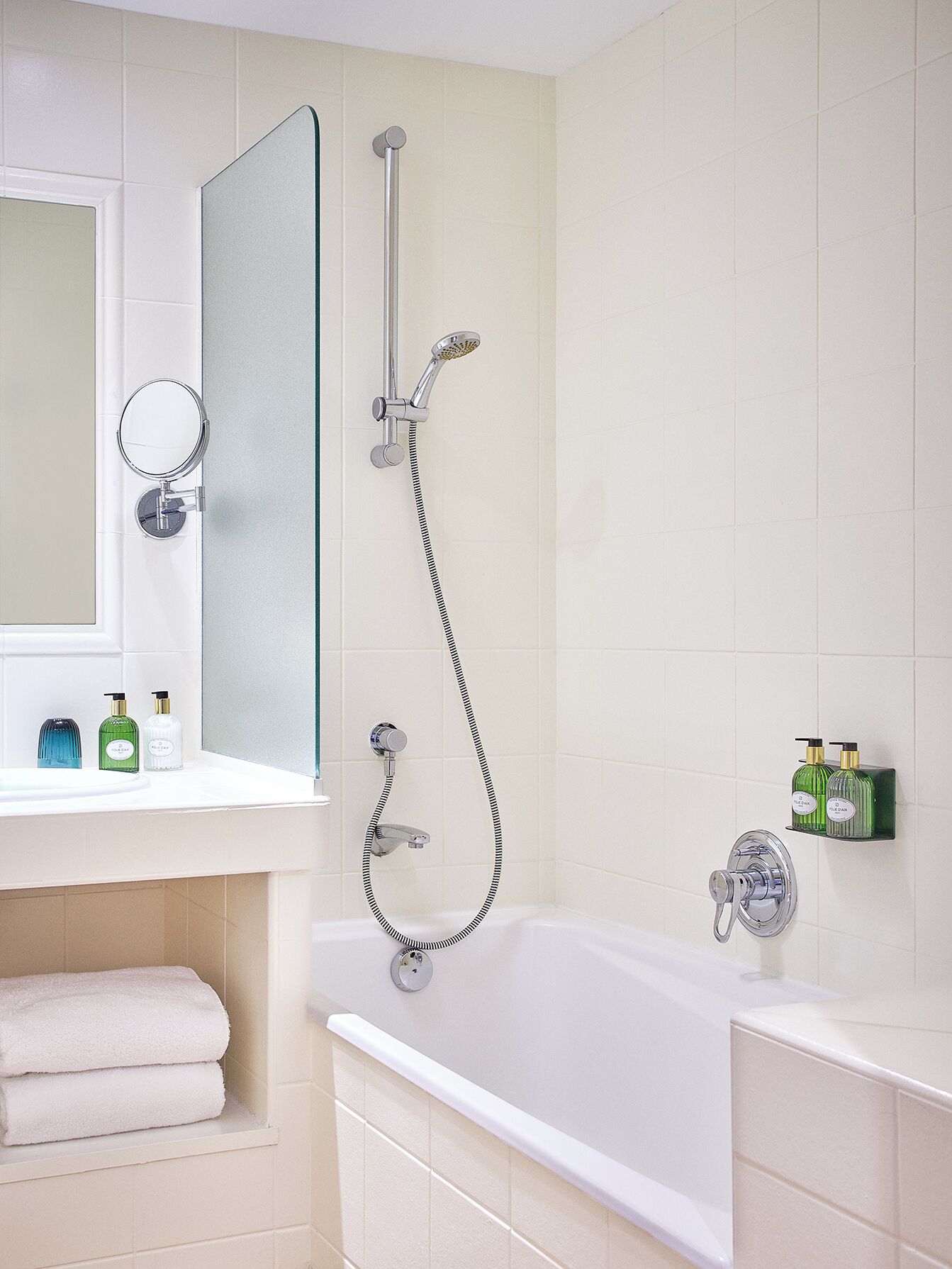A bathroom with a bathtub, a shower, a sink with a mirror, and toiletries.