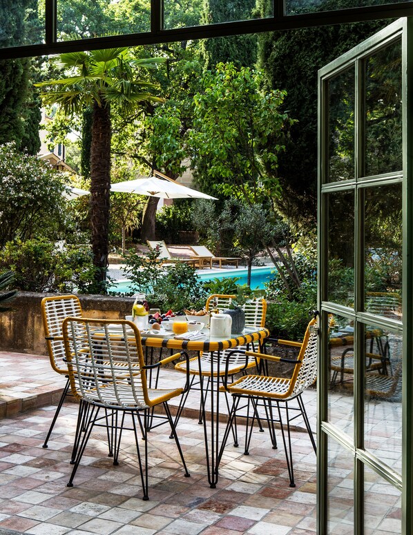 An outdoor dining area with wicker chairs and a table set for breakfast.