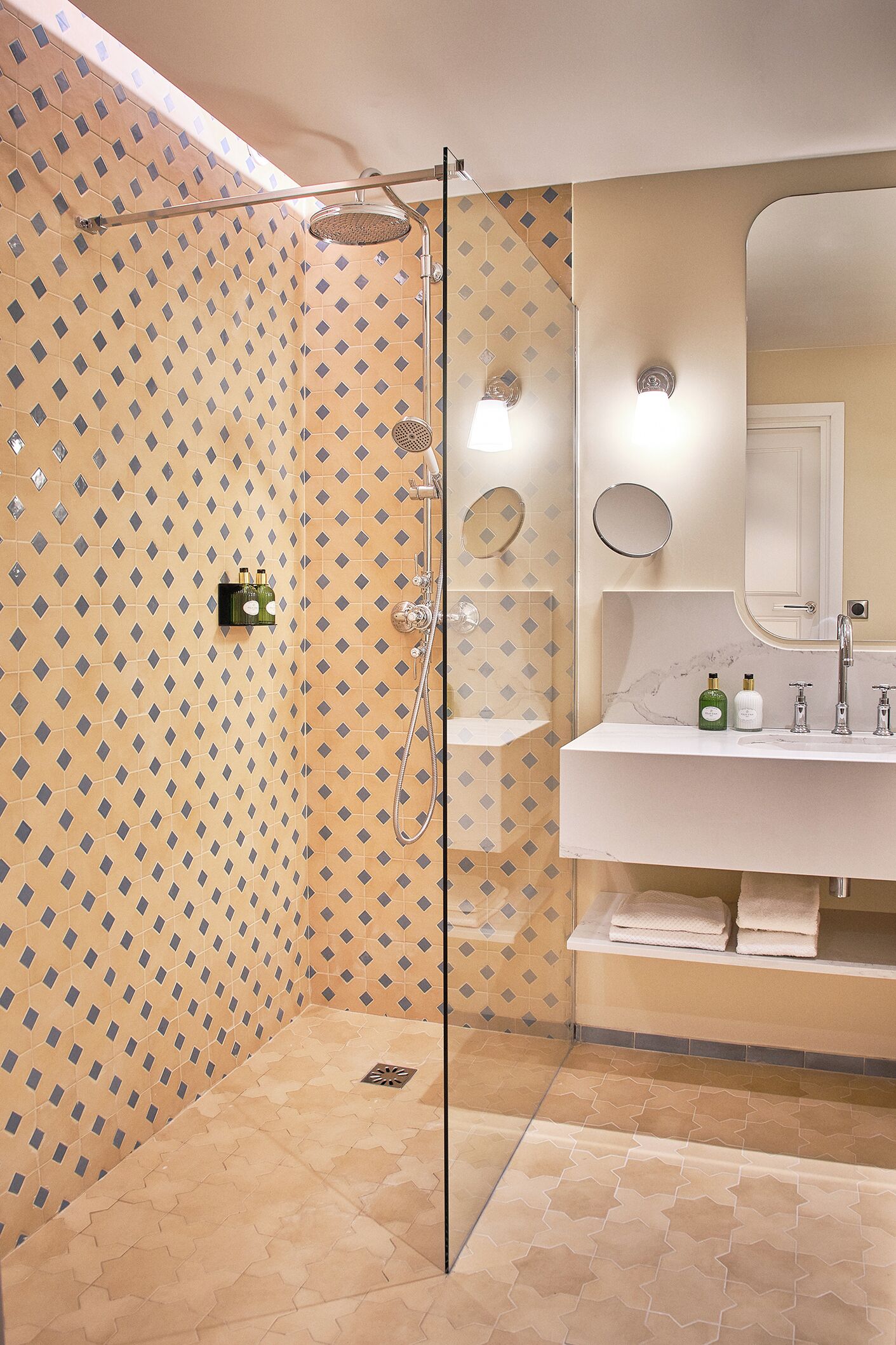 A bathroom with a shower, a sink with a mirror, and patterned walls.