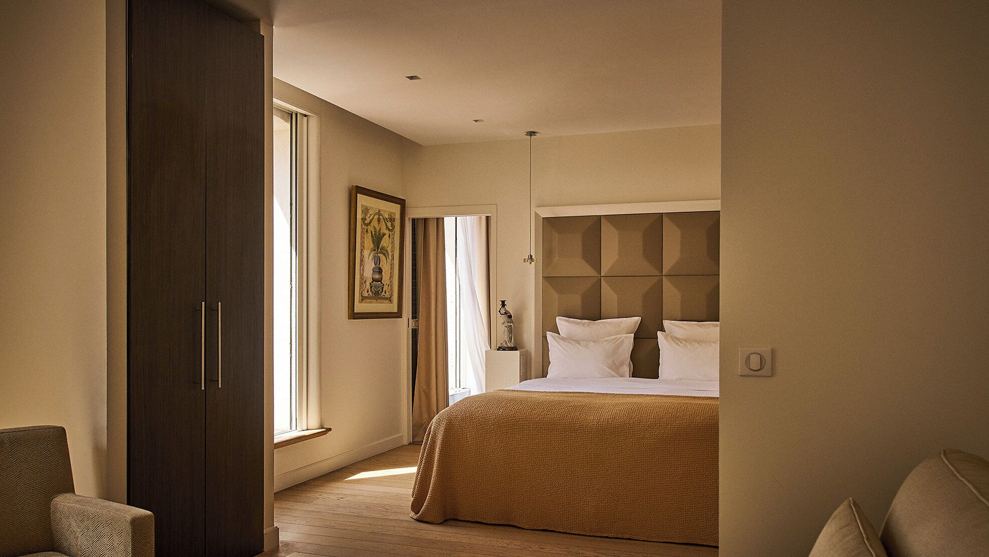 A bedroom with a large bed, a wardrobe, a window, and a painting.
