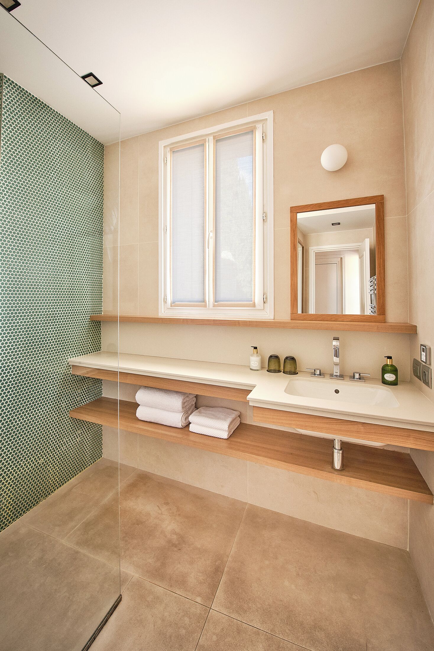Un baño moderno con un espejo grande, dos lavamanos y una cabina de ducha de vidrio.