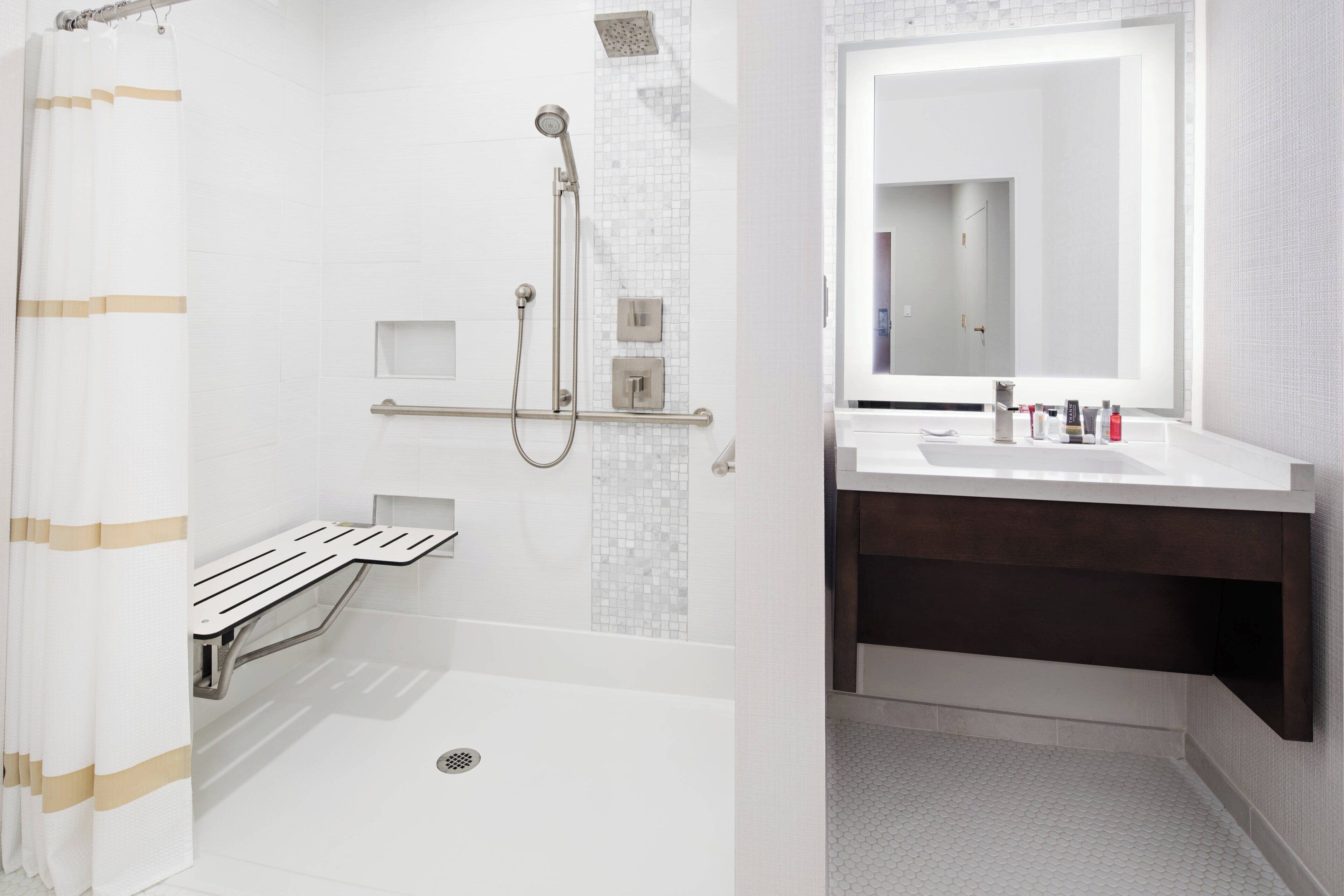 A modern bathroom with a shower, a toilet, and a sink with a mirror.