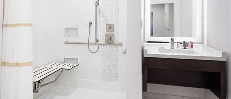 A modern bathroom with a shower, a toilet, and a sink with a mirror.
