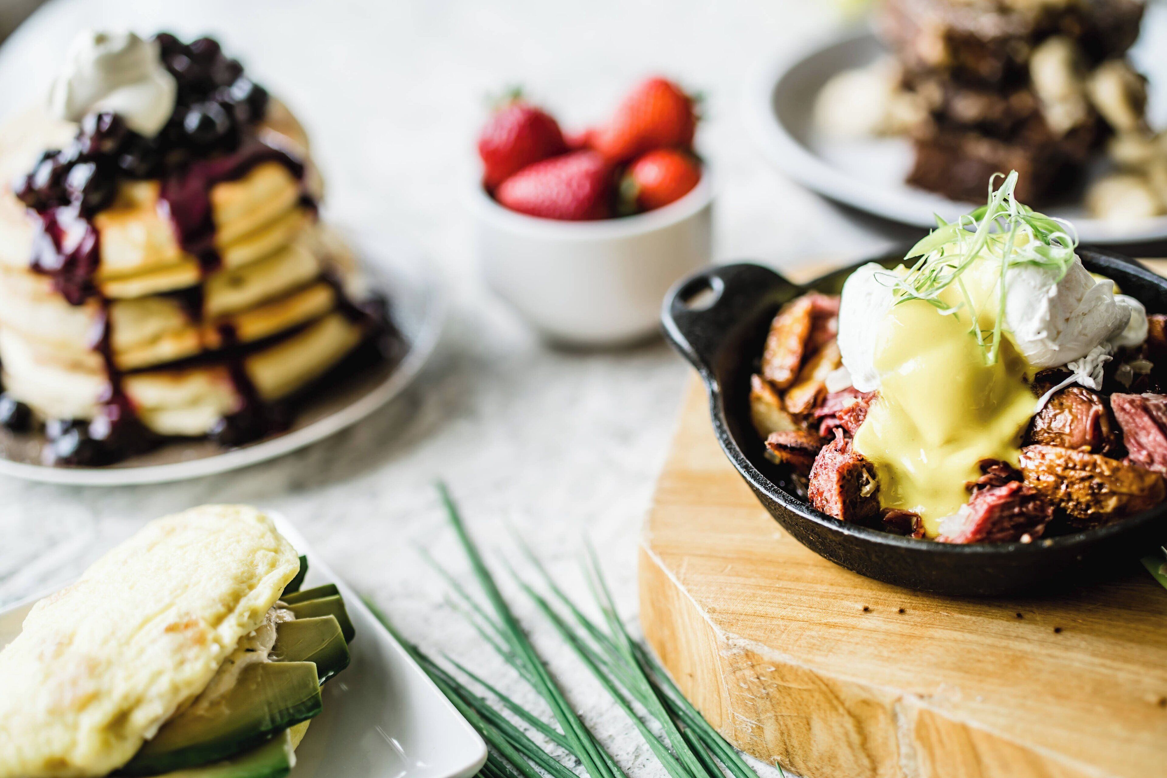 A breakfast setting with pancakes, steak, and strawberries.