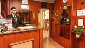 Mostrador de recepción de hotel con detalles de madera, un reloj y un cartel que indica el área de servicio a cuartos.