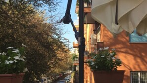 Un balcón con una mesa, plantas en macetas y un edificio con balcones al fondo.