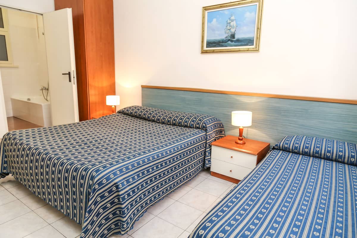 A hotel room with a bed, bedside table, and a painting on the wall.