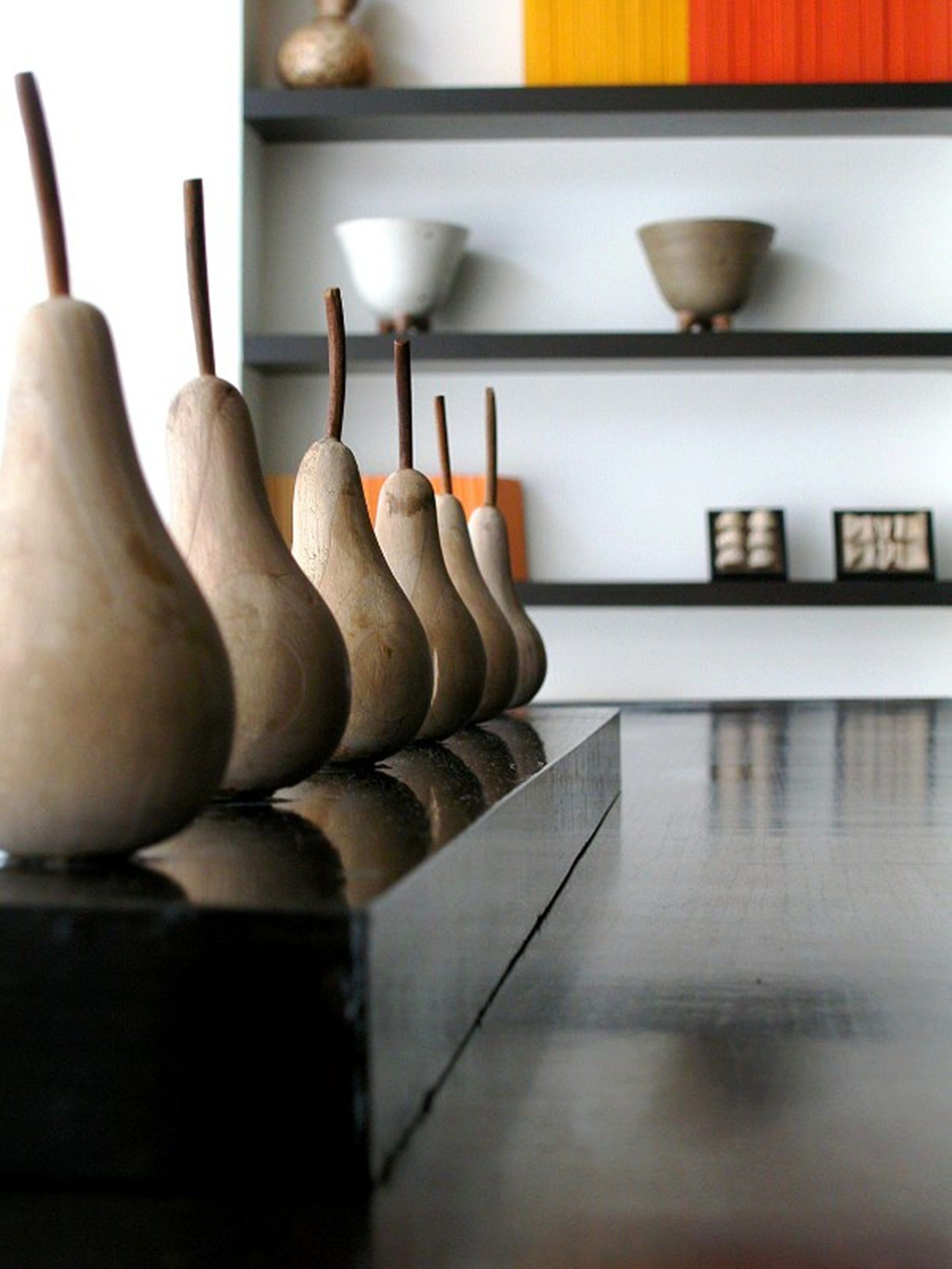 A row of wooden vases on a reflective surface.