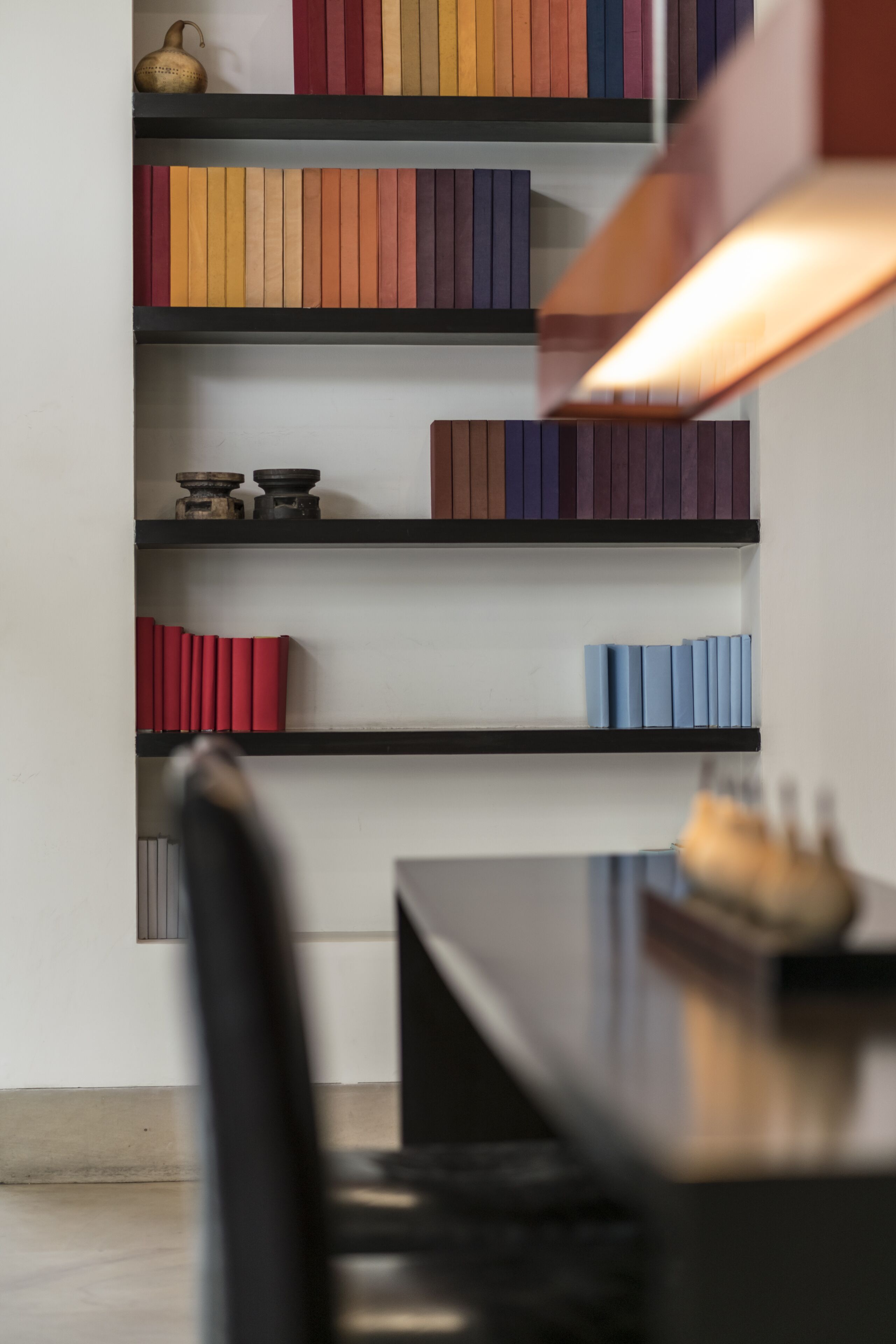 Una estantería moderna con varios libros y objetos decorativos.