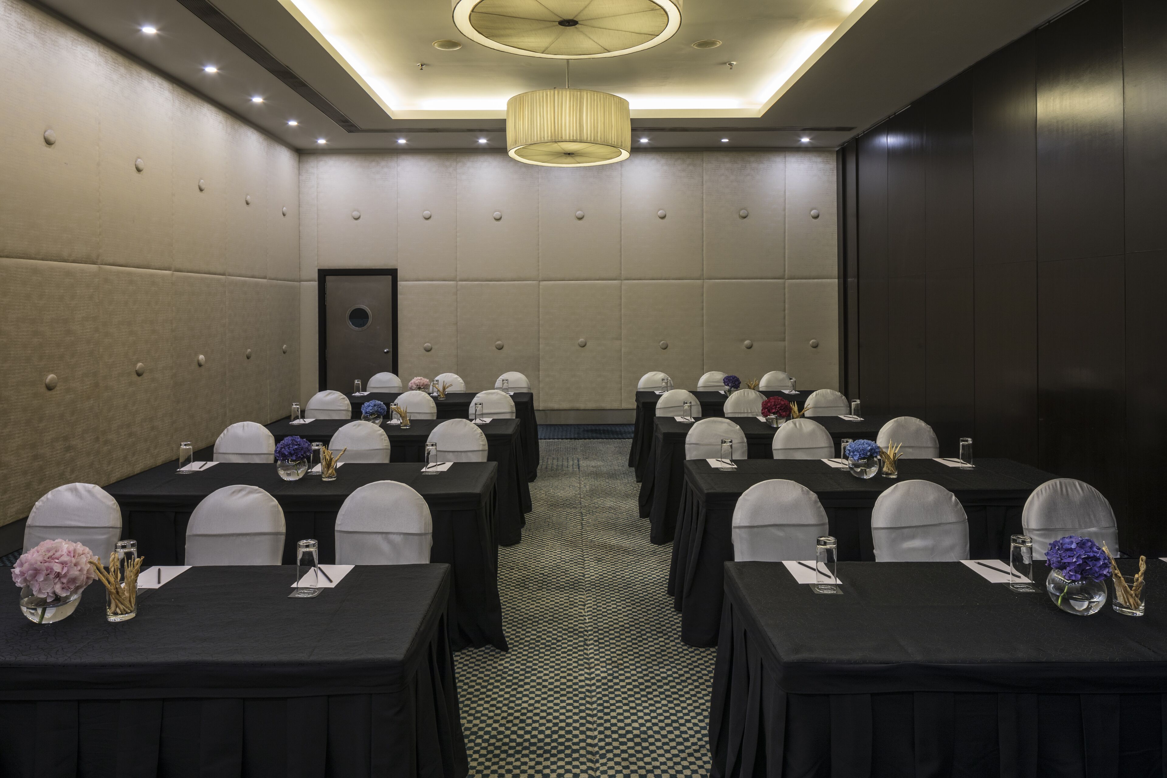 A conference room with tables and chairs, a chandelier, and a patterned floor.