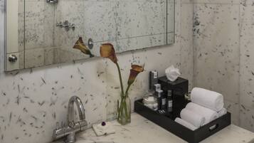 A bathroom with a marble sink, a mirror, a towel rack, and toiletries.