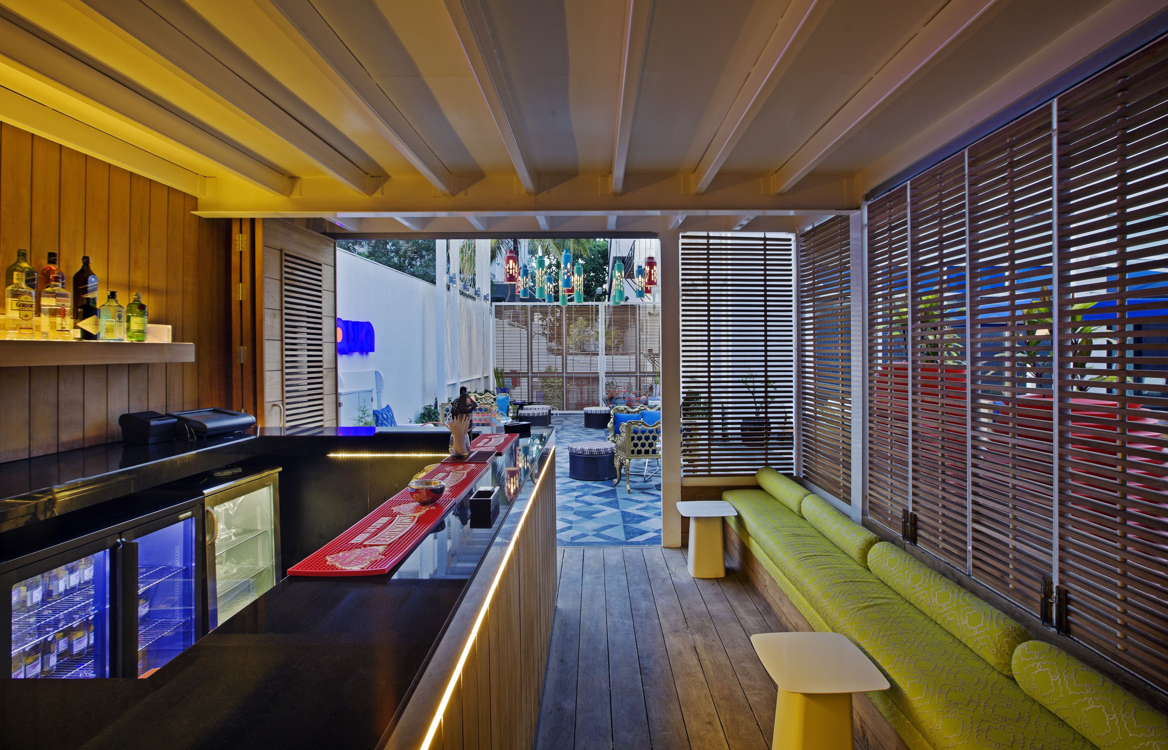 A modern bar area with a wooden counter, seating, and a view through the window.