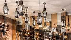 Un espace bar agrémenté de guirlandes lumineuses décoratives, d’un mur miroir et de différentes bouteilles exposées sur des étagères.