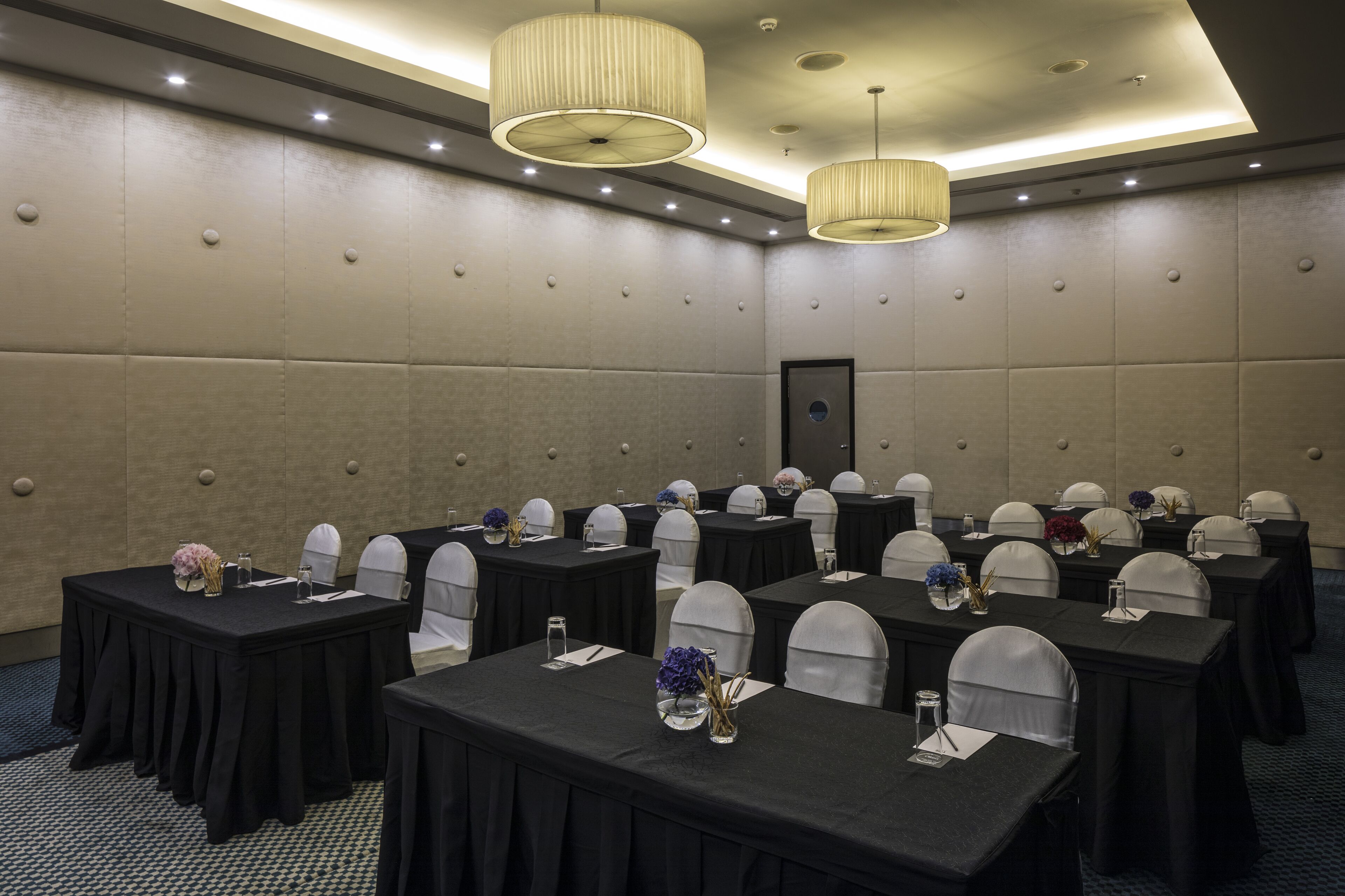 A conference room with multiple tables, chairs, and a large door.