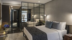 Une chambre moderne avec un grand lit, un miroir et une vue sur une autre pièce.