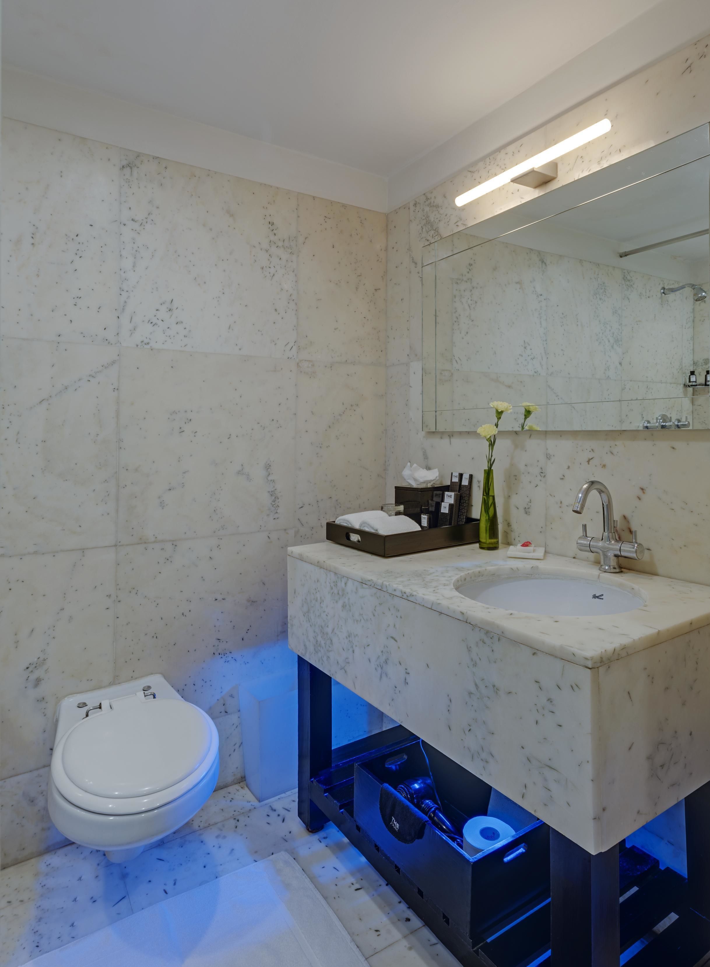 A modern bathroom with a marble sink, a toilet, and a mirror.