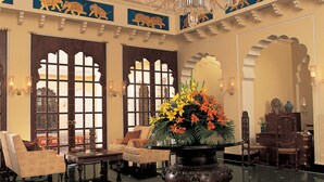 A lobby with a chandelier, a large vase with flowers, and traditional decor. - The Oberoi Vanyavilas, Ranthambore (Sawai Madhopur)